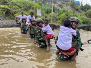 Satgas TNI Bantu Anak-Anak Kampung Dal Seberangi Sungai Berangkat Ke Sekolah